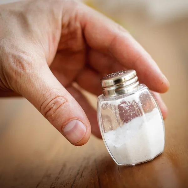 Agitador de sal tomado por mano masculina — Foto de Stock