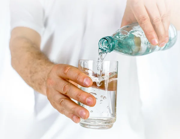 Мужчина разливает воду из бутылки в стекло — стоковое фото