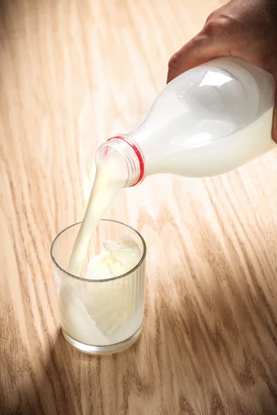 Fresh milk poured from bottle to glass — Stock Photo, Image