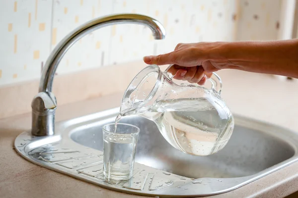 Main verser de l'eau dans le verre — Photo