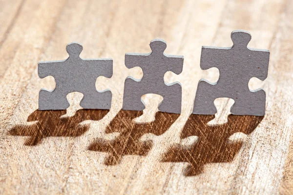 Three Jigsaw Puzzle Pieces on Table Lit by Back light — Stock Photo, Image