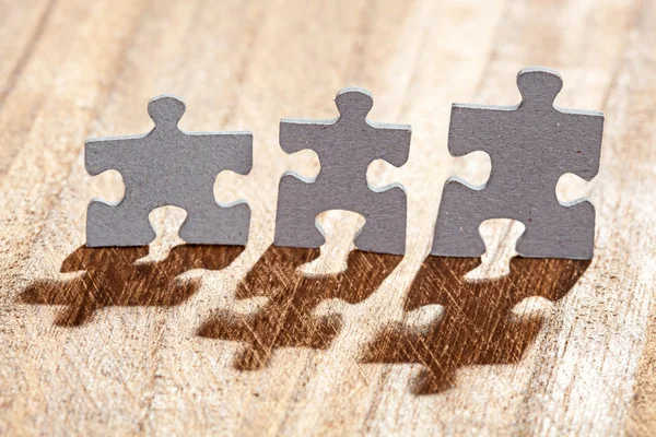 Drie stukken van de puzzel op tabel verlicht door terug licht — Stockfoto