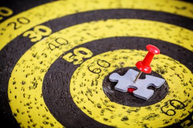 Adam şekil jigsaw bulmaca parçası eski hedef tahtası üzerinde kırmızı pin sıkışmış