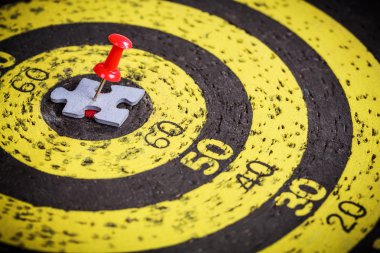 Adam şekil jigsaw bulmaca parçası eski hedef tahtası üzerinde kırmızı pin sıkışmış