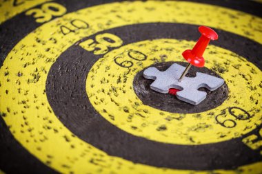 Adam şekil jigsaw bulmaca parçası eski hedef tahtası üzerinde kırmızı pin sıkışmış
