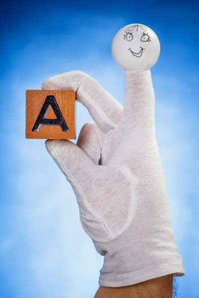 Finger puppet holding wooden cube with capital letter A — Stock Photo, Image