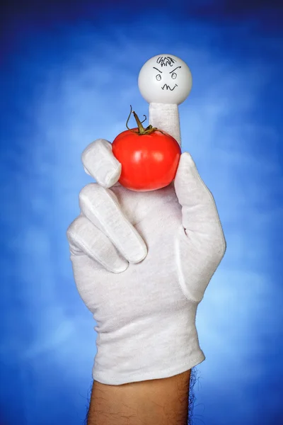 Angry finger puppet holding tomato fruit