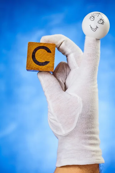 Fantoche dedo segurando cubo de madeira com letra maiúscula C — Fotografia de Stock