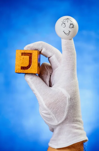 大文字 J で木製の立方体を保持している人形の指 — ストック写真