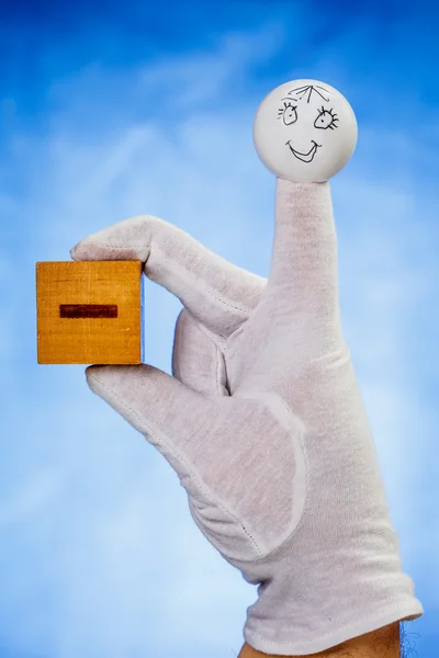 Finger puppet houden houten kubus met minteken — Stockfoto