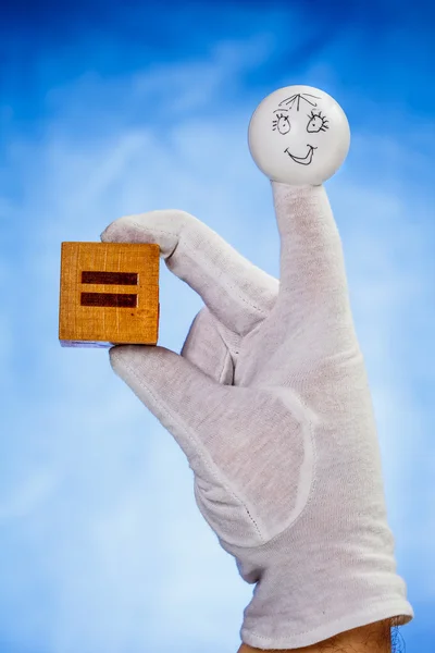 Finger puppet houden houten kubus met gelijkteken — Stockfoto