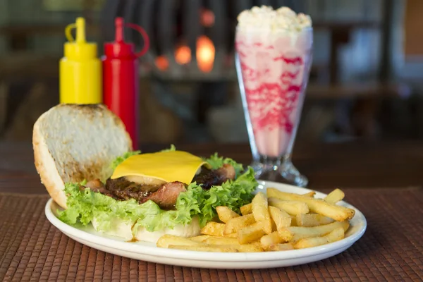 Hambúrguer e batatas fritas com um batido Imagens De Bancos De Imagens