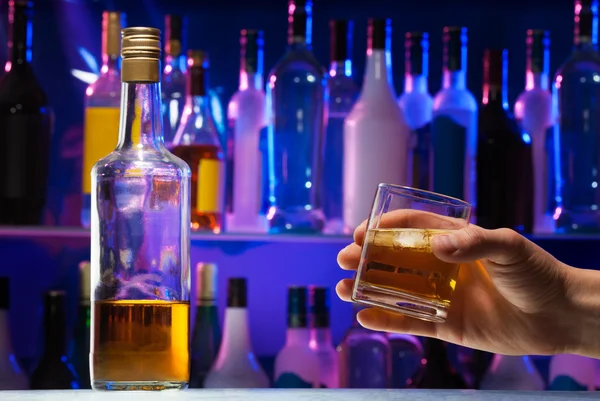 Bottle with whiskey and glass in man hand — Stock Photo, Image