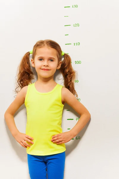 Soporte de niña midiendo la escala de altura —  Fotos de Stock