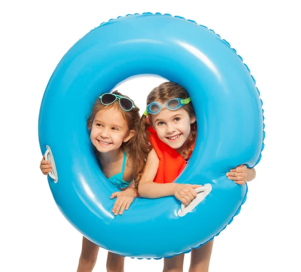 Девушки, выглядывающие из большого синего резинового кольца — стоковое фото