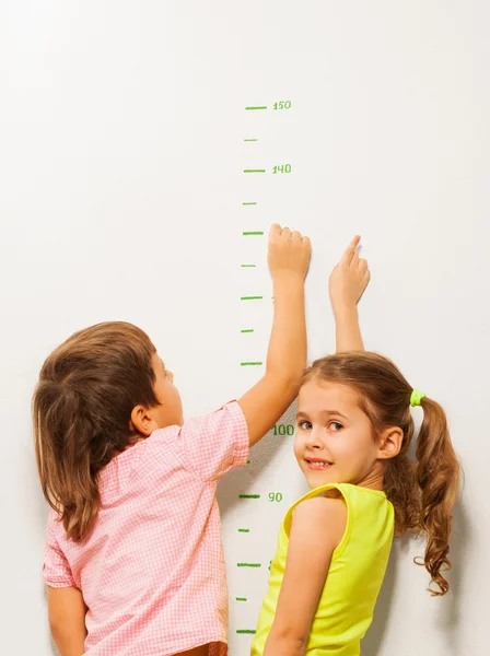 Dos niños leen la altura en la pared del hogar —  Fotos de Stock