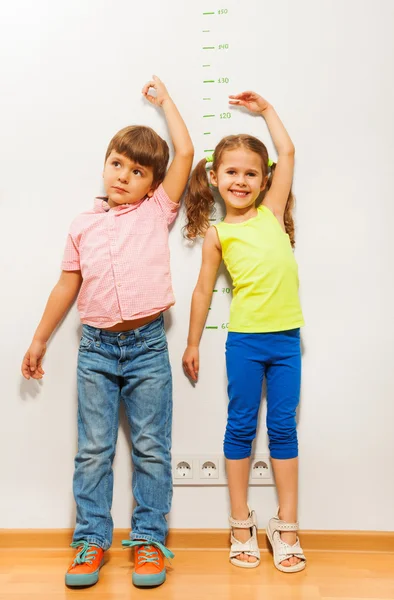 Junge und Mädchen prüfen Höhe auf Wandwaage — Stockfoto