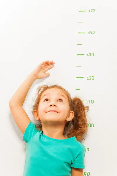 Girl measure height with hand looking up — Stock Photo, Image