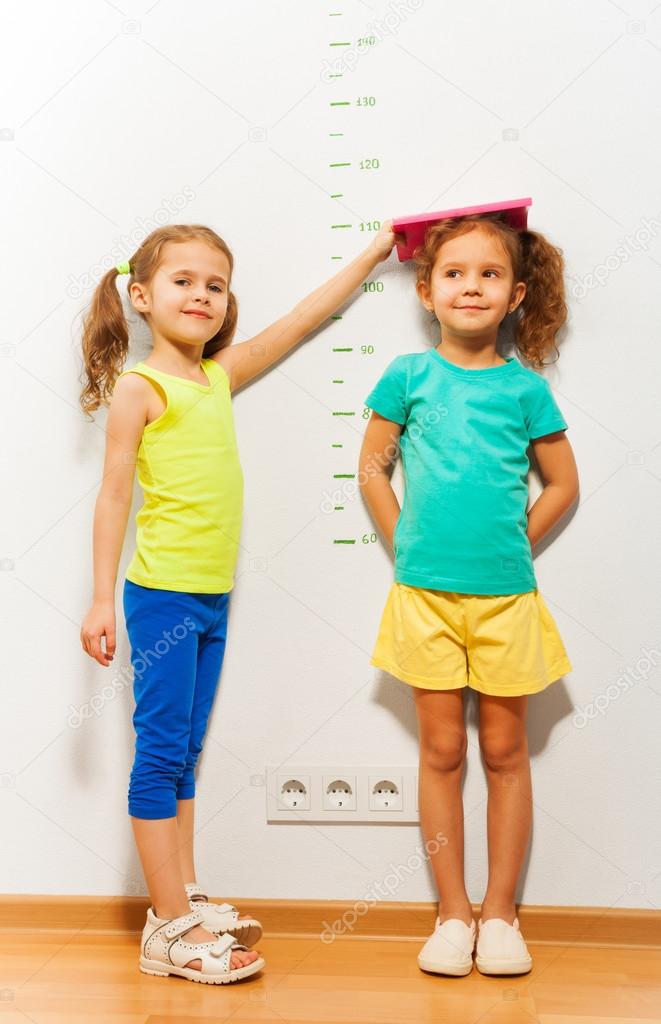 Two girls near scale on wall