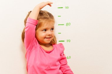 Height measurement by little girl at the wall clipart