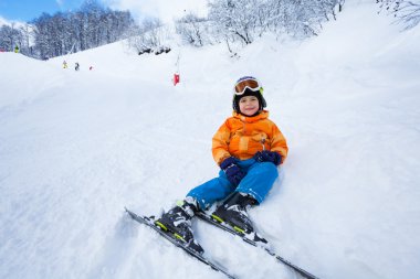 Küçük çocuk dinlendikten sonra oturup karda Kayak ders