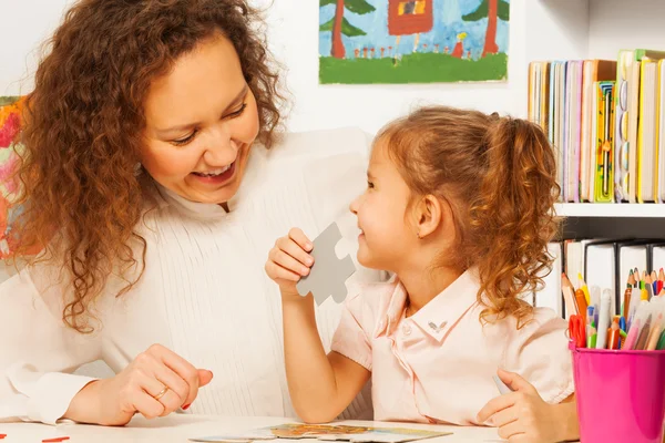 Leraar helpen meisje te monteren een puzzel — Stockfoto