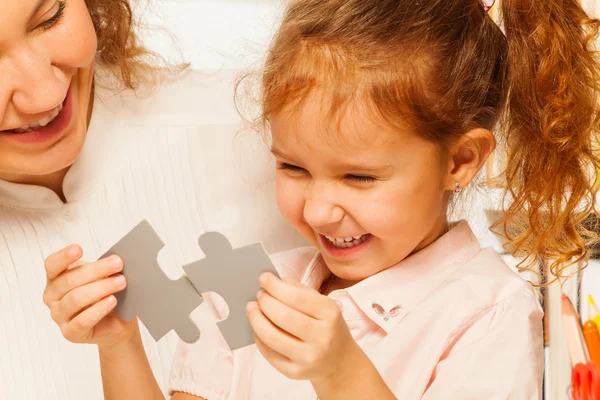 Pequeña colegiala intenta montar rompecabezas — Foto de Stock