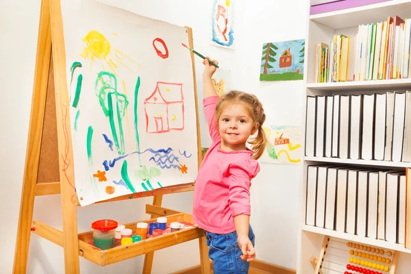 Chica pintando con pincel verde en el caballete — Foto de Stock