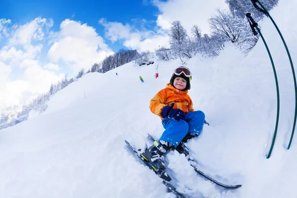 Niño sentarse con esquí en la nieve descansando —  Fotos de Stock