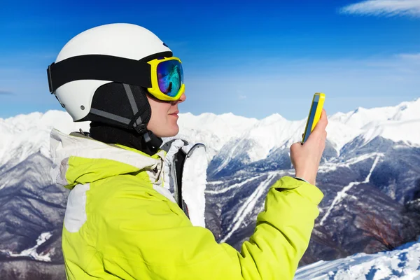 Skier woman with cell phone over mountains — Stock Photo, Image