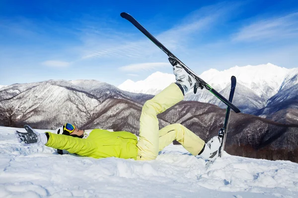 Kvinnan låg i snön och lyfta benen med ski — Stockfoto