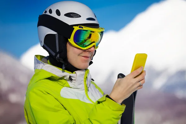 Mulher esquiador olhar para cima no telefone inteligente — Fotografia de Stock