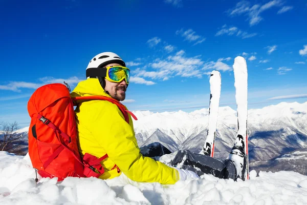 Esquiador con mochila sentarse en la cima de la montaña —  Fotos de Stock