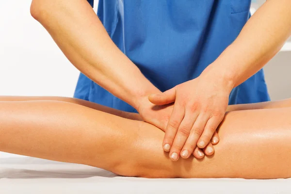 Masseur's hands kneading female leg — Stock Photo, Image