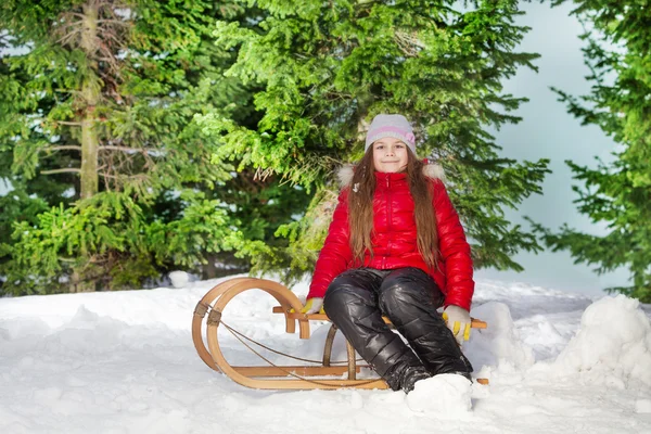 Girl sitting on wooden sledge — Stock Photo, Image