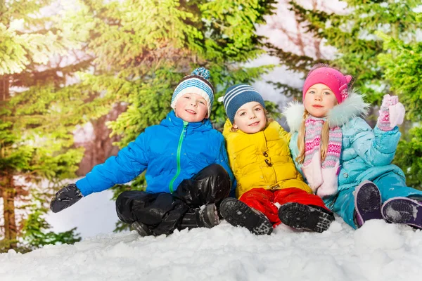 Chlapci a dívka sedí v sněhu — Stock fotografie