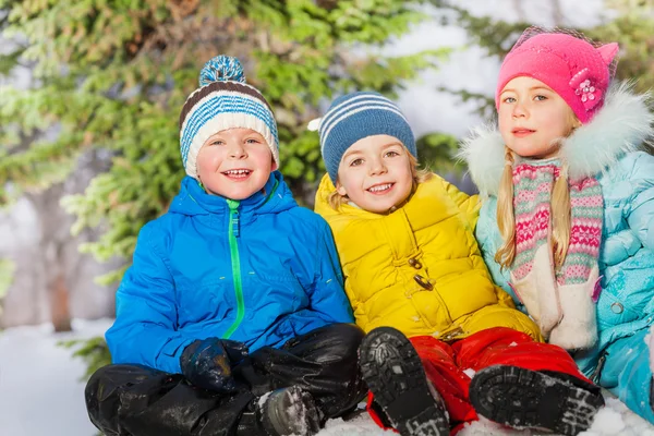 Små barn sitter i snö — Stockfoto