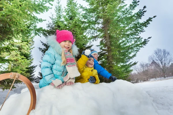 Meninos e menina atrás da fortaleza de neve — Fotografia de Stock