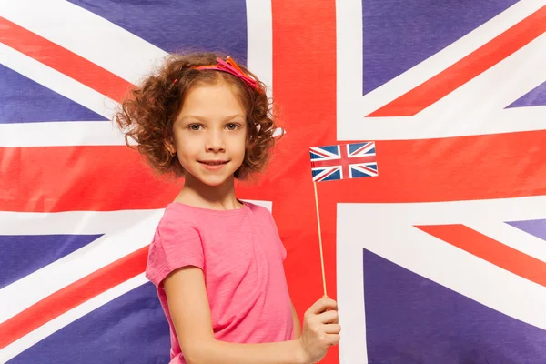 Девушка с флагом перед британским флагом — стоковое фото