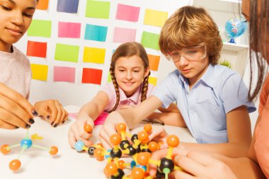  boy and girls assembling molecule model