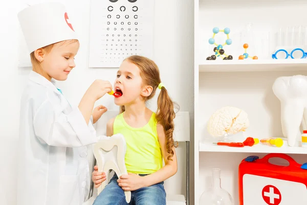 Girl playing a dentist with her friend — Stock Photo, Image