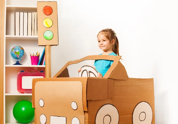 Menina dirigindo seu carro de papelão de brinquedo — Fotografia de Stock