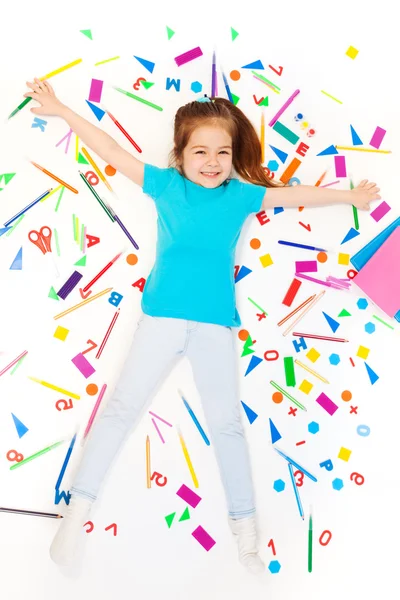 Girl laying among heap of  stationery — Stock Photo, Image