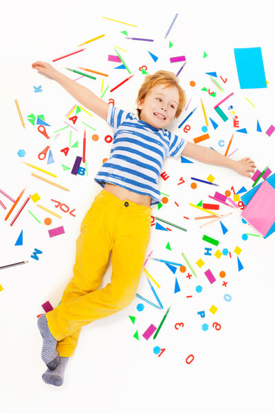 boy laying in the middle of office supplies 