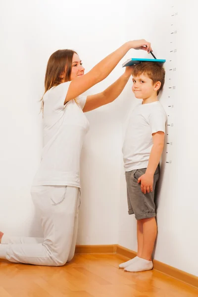 Mother measuring her son's height — Stock Photo, Image