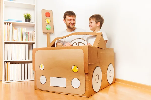 Padre e hijo conduciendo coche de cartón — Foto de Stock