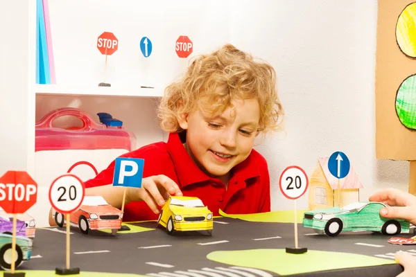 Мальчик играет в игрушечные бумажные автомобили — стоковое фото