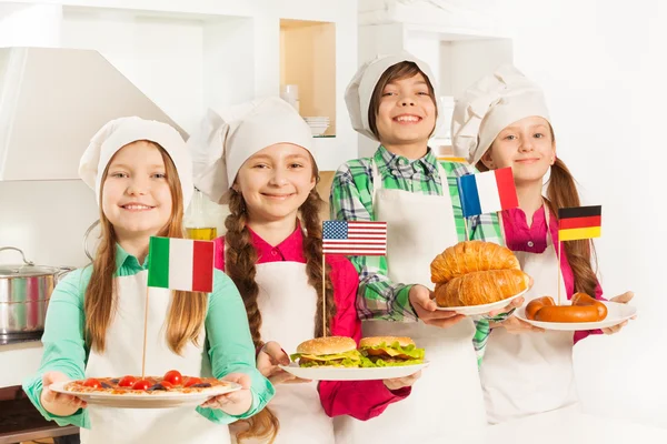 Четыре юных повара держат тарелки — стоковое фото