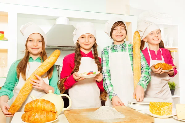 Quatro jovens cozinheiros com croissants — Fotografia de Stock