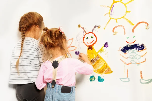 Два маленьких художника рисуют у стены — стоковое фото